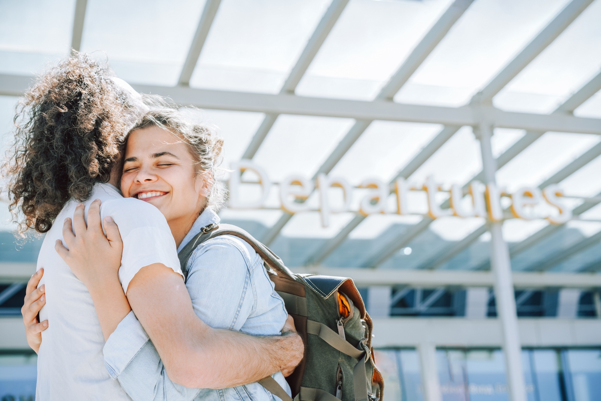 Beautiful couple in love hugging, telling goodbye at the airport Departures area