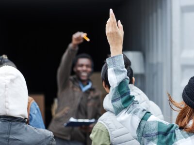 Close up of young woman raising hand at outdoor auction