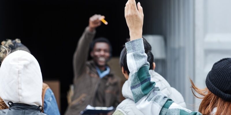 Close up of young woman raising hand at outdoor auction