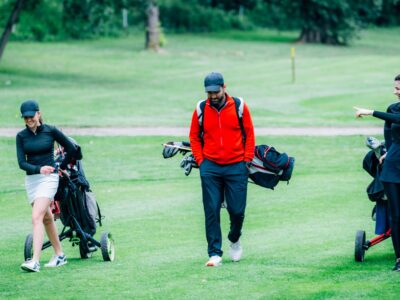 Golf training. Two young ladies with golf instructor having a lesson on a golf course