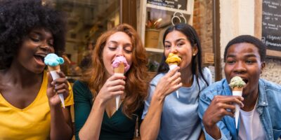 Multi-ethnic friends in an ice cream parlor eating ice cream, summer fun, sucking on ice cream