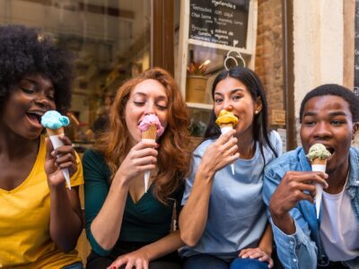 Multi-ethnic friends in an ice cream parlor eating ice cream, summer fun, sucking on ice cream