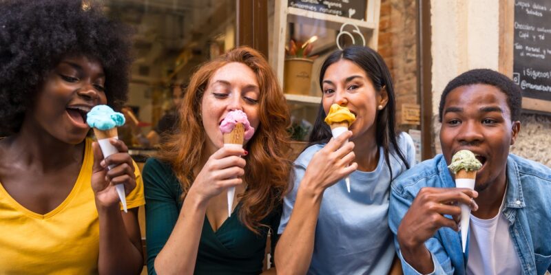 Multi-ethnic friends in an ice cream parlor eating ice cream, summer fun, sucking on ice cream
