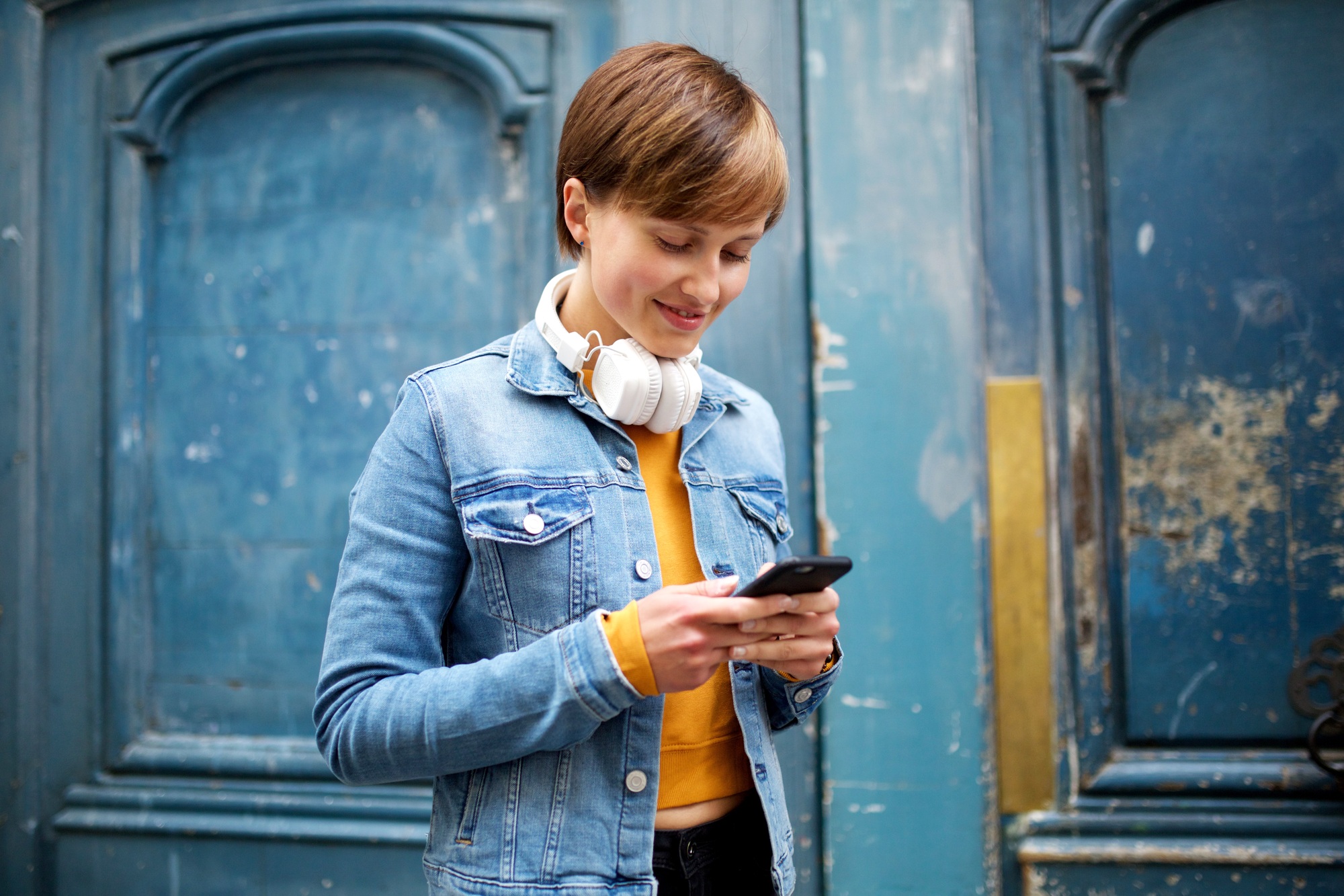 Portrait cool young woman sending text message with mobile phone