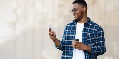 Portrait of african american guy texting sms on smart phone