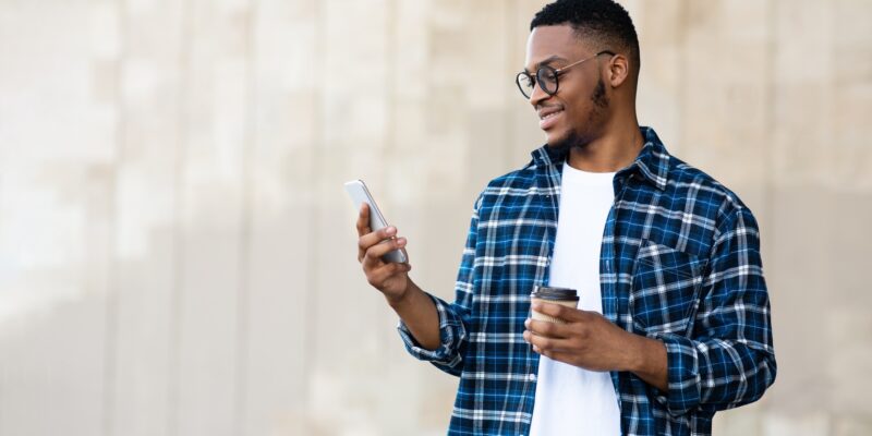Portrait of african american guy texting sms on smart phone