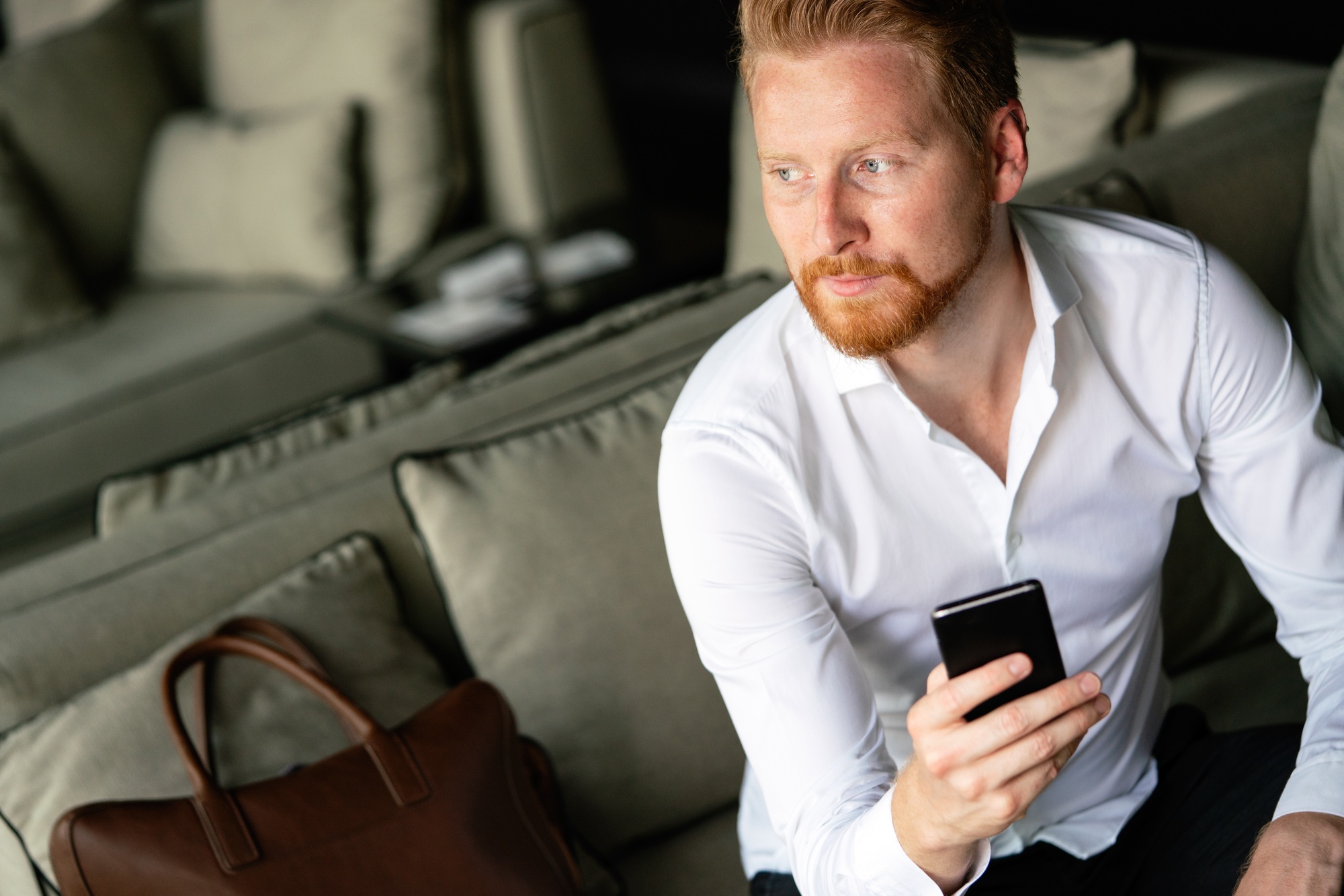 Young businessman sending message with mobile phone